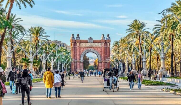 A wide, open street in sunny Barcelona, Spain filled with strolling pedestrians
