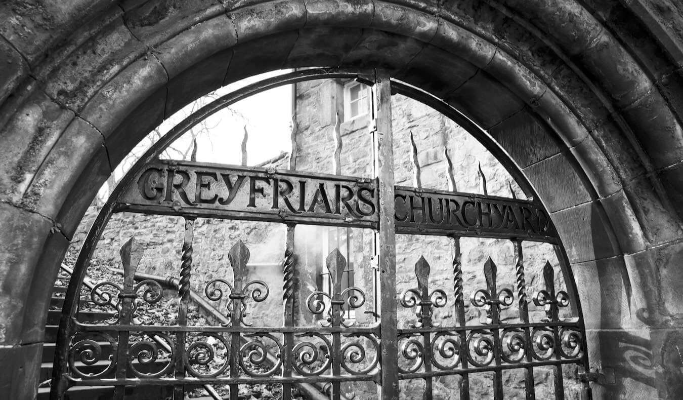 A black and white photo of the Greyfriars church gate in spooky Edinburgh, Scotland
